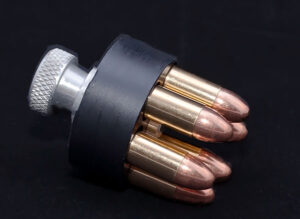 Closeup of a speed loader with bullets ready to be loaded into a revolver cylinder.