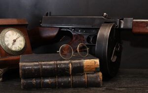 Old time law books, some reading glasses, a clock, and a Thompson sub-machine gun.