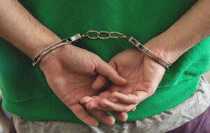A person's hands are shown handcuffed behind their back
