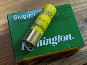 A box of slugs with one of the shotgun shells on top of the box.