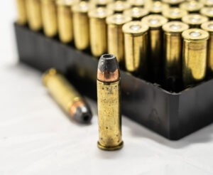 A tray of hollow point bullets with two outside the tray, one standing, one resting