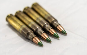 Four green-tipped steel penetrator rounds side by side, resting on side