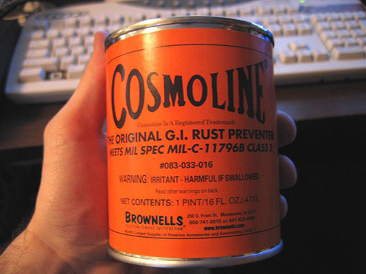 A hand holds up a can of Cosmoline in closeup