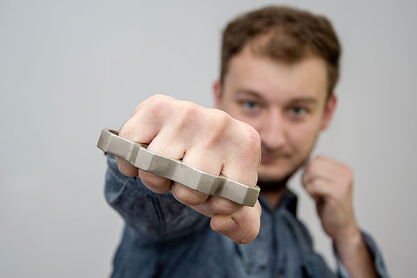 A man demonstrates full extension of a punch while wearing brass knuckles
