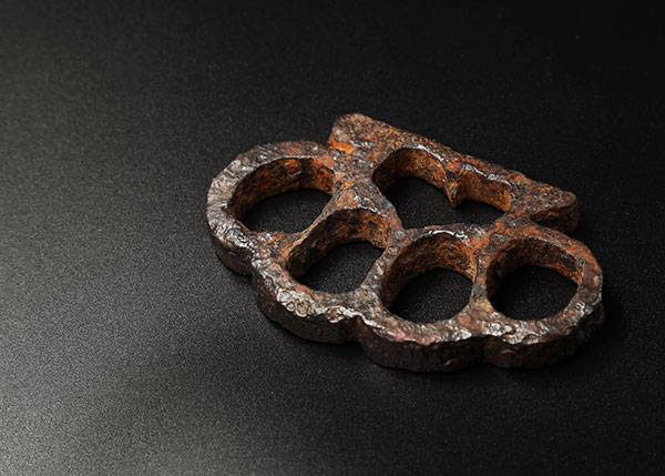 A worn, roughly cast set of antique brass knuckles in dramatic lighting